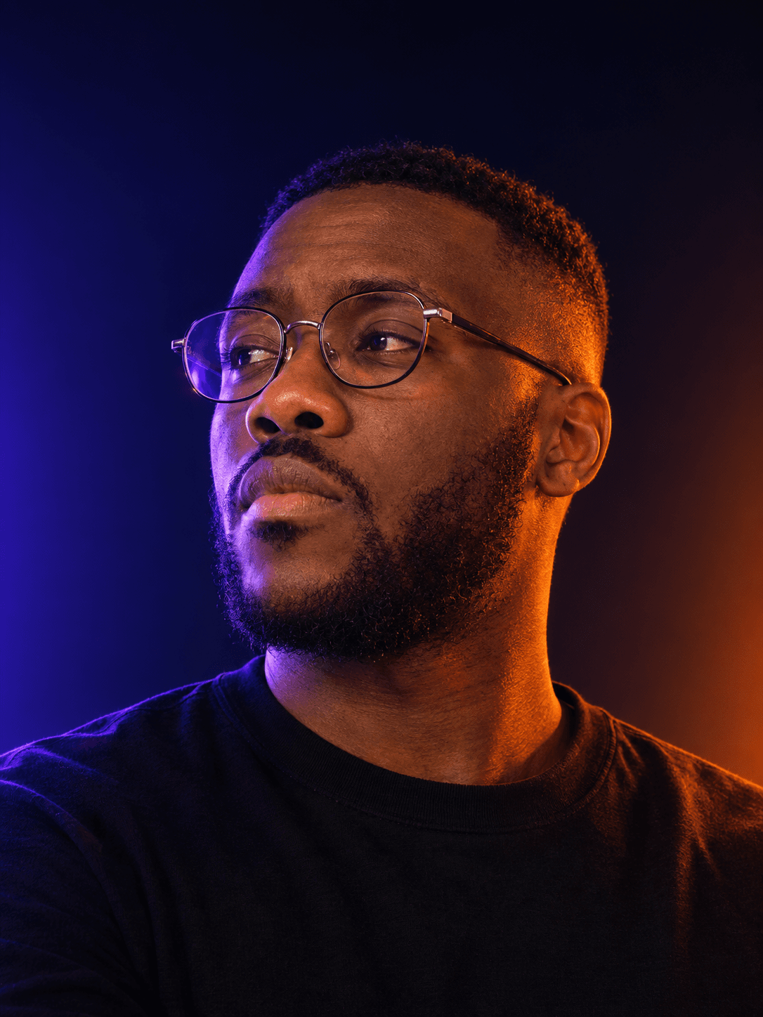 Salif N'diaye, lit by violet and amber desk lighting